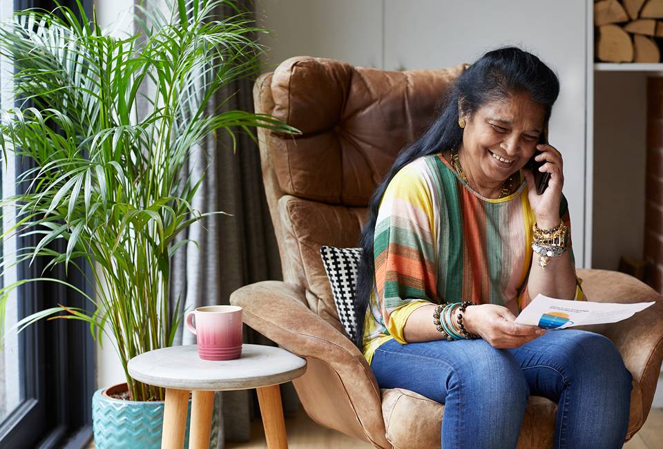 A woman on the phone dealing with a bill - she is smiling