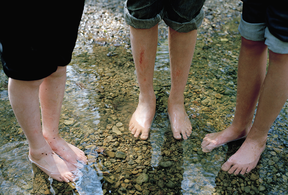 Three peoples' feet in a river
