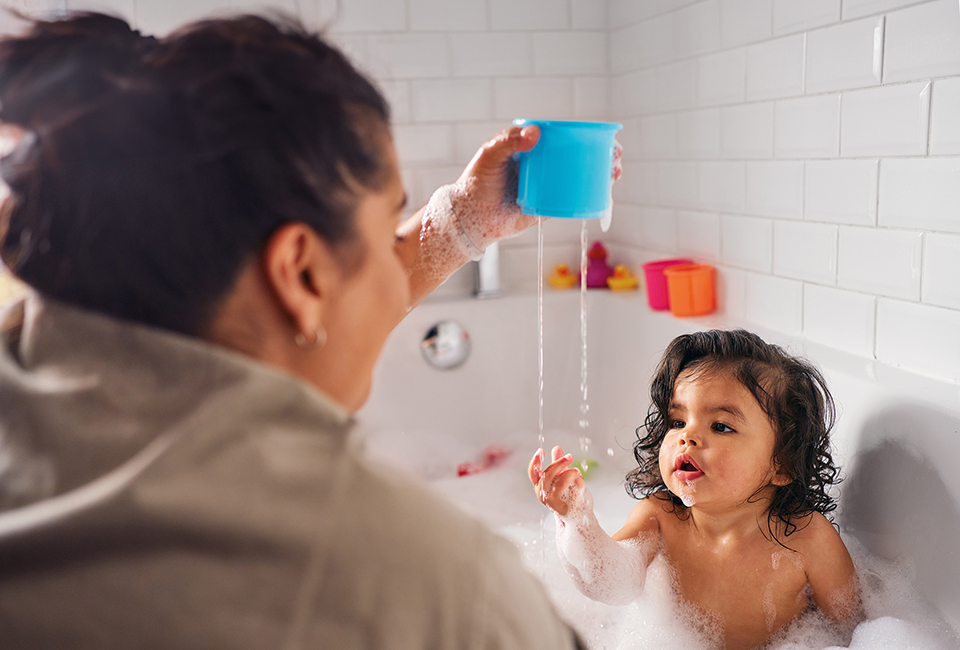 Mum playing with little girl in bath