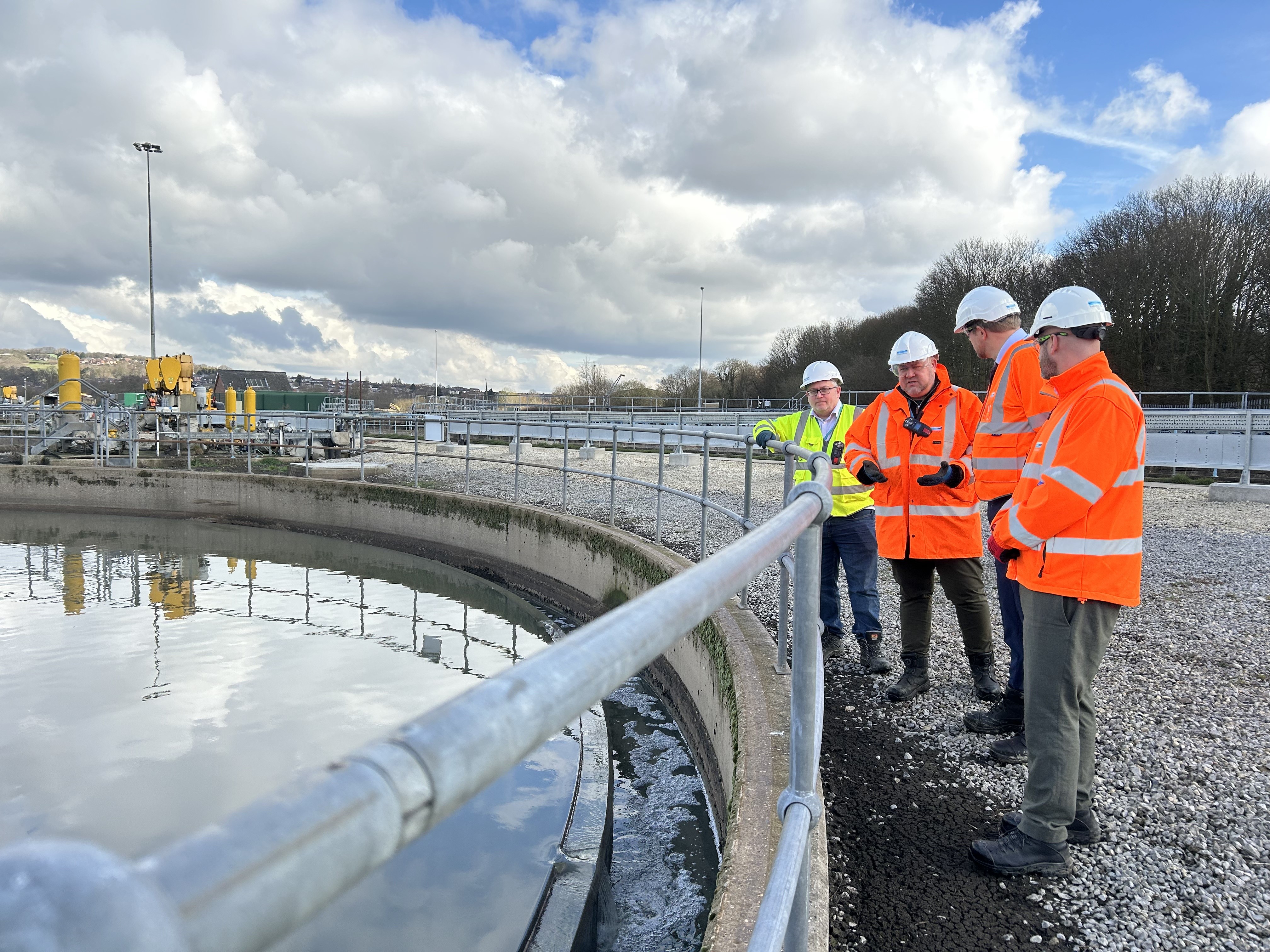 people in safety wear stood by the edge of a large water tank