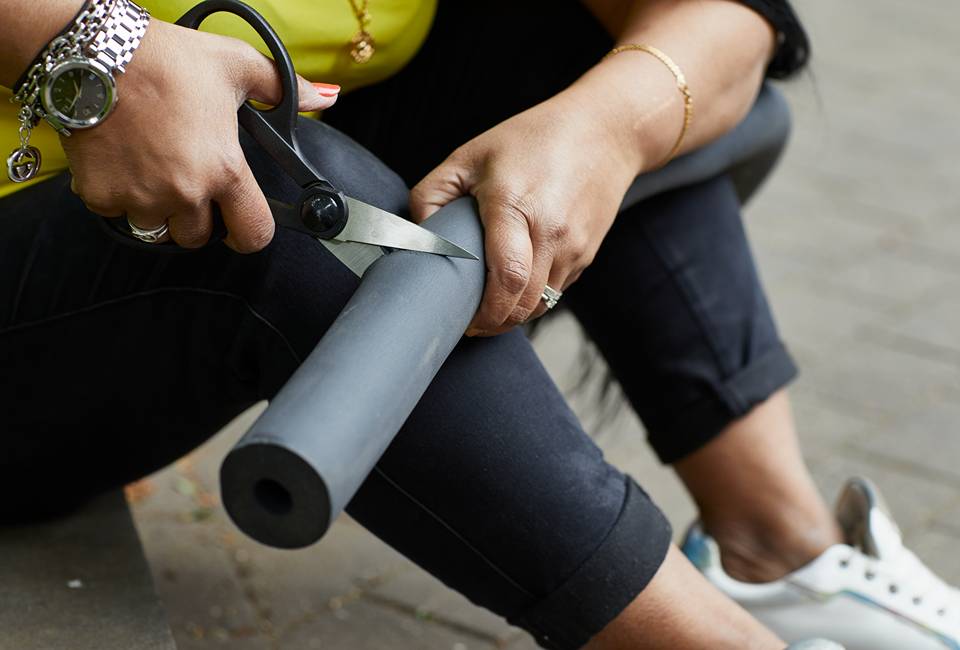 Person cutting pipe insulation